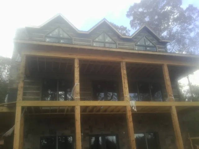 Dormers and porch framing on a large log home under construction — Roof Coating work by our crew in Mendon